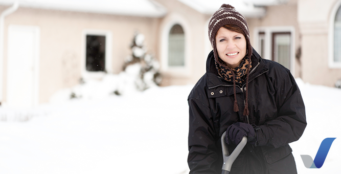 Woman shoveling snow from her house in winter