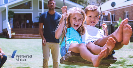 Man pushes two children on a swing in front of his home